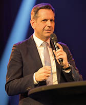 Olaf Lies, Ministerpr sident des Landes Niedersachsen, spricht auf der B hne w hrend der Gala. Er steht vor einem dunkelblauen Hintergrund mit einem hellen Lichstrahl von oben nach unten.